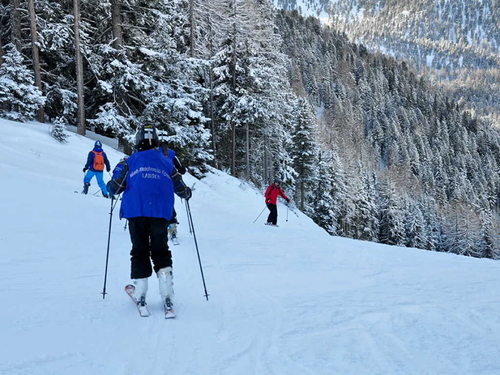 Zwei Skifahrende auf einer Waldpiste.